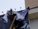 Фото 1 - монтаж баннера на троссовую раму на здание.